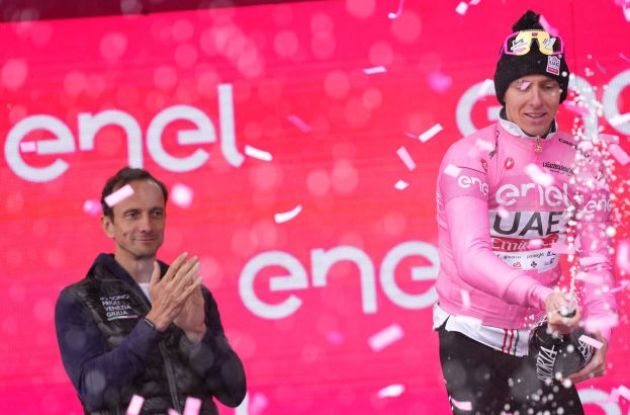 Tadej Pogacar wearing pink jersey celebrating with champagne on Giro d'Italia podium