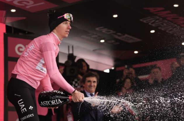 Tadej Pogacar celebrating his Giro d'Italia lead with champagne on the podium