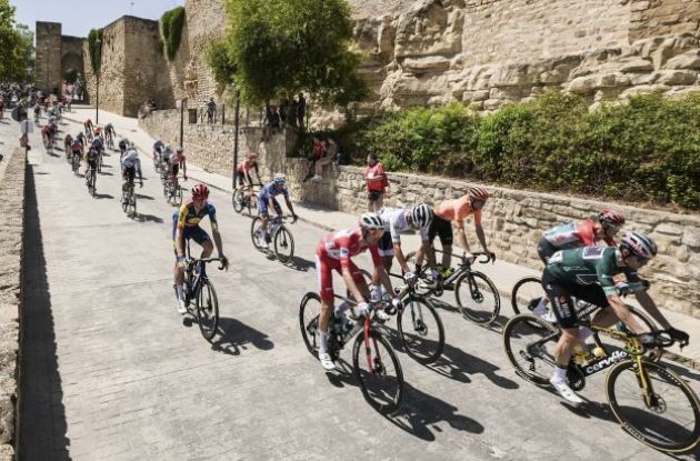 Vuelta a Espana cyclists ride by historic walls