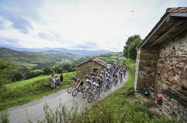 Vuelta peloton riding by Spanish mountain cabins