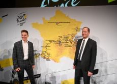 Tadej Pogacar and Christian Prudhomme smiling in front of 2023 Tour de France map