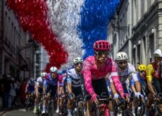 | A.S.O. Cyclists passing under tricolore in French village during Tour de France