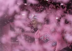 Tadej Pogacar wearing pink jersey celebrating with champagne on Giro d'Italia podium