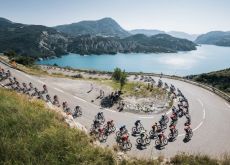Tour de France cyclists in French Alps with mountain lake