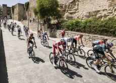 Vuelta a Espana cyclists ride by historic walls