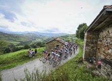 Vuelta peloton riding by Spanish mountain cabins